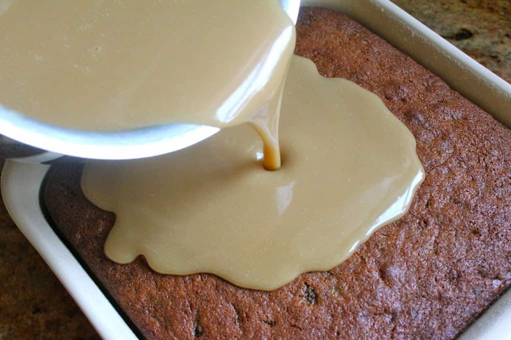 pouring the sticky toffee sauce on the cake