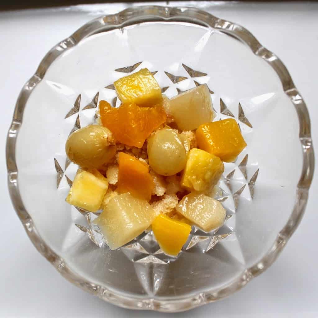 fruit cocktail on cake layer in a bowl, overhead view