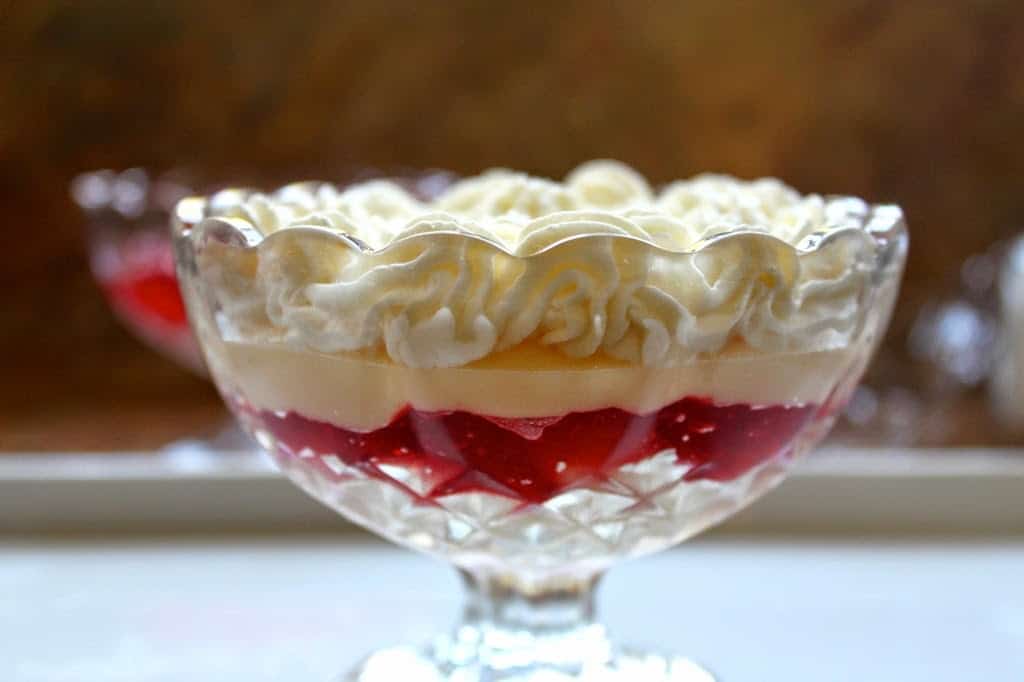 sideview of an individual English trifle showing cream, custard, and jello