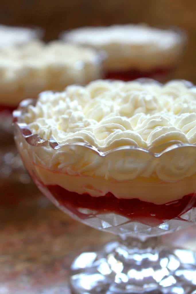 close up of individual english trifles with layers of cream, custard and jello