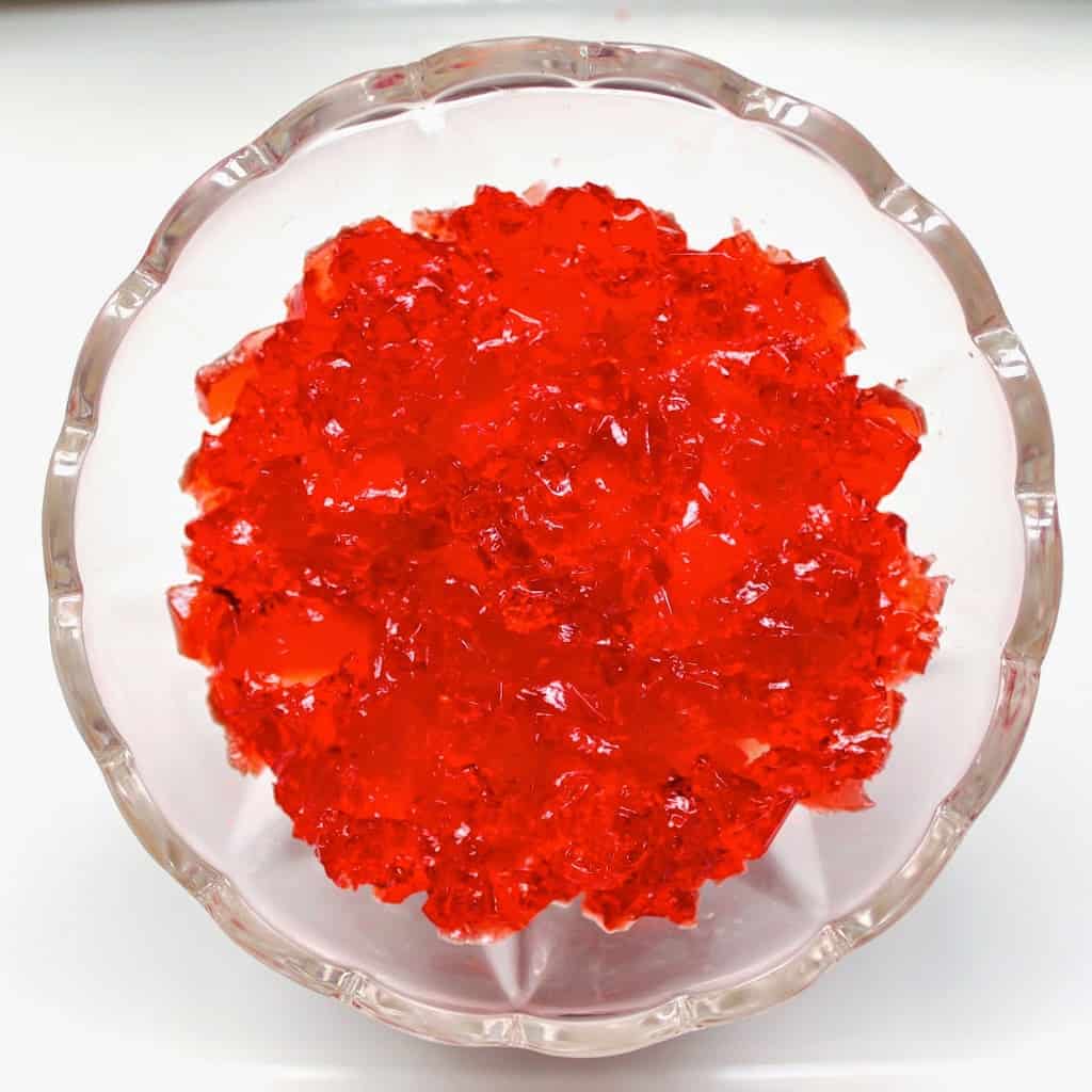 red jello or gelatin in a bowl on top of cake and fruit, overhead view