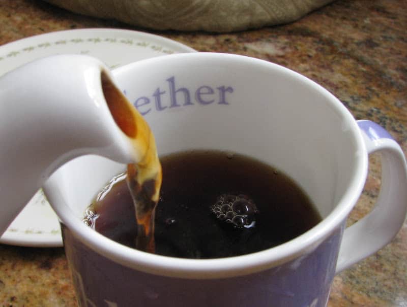pouring black tea into a mug
