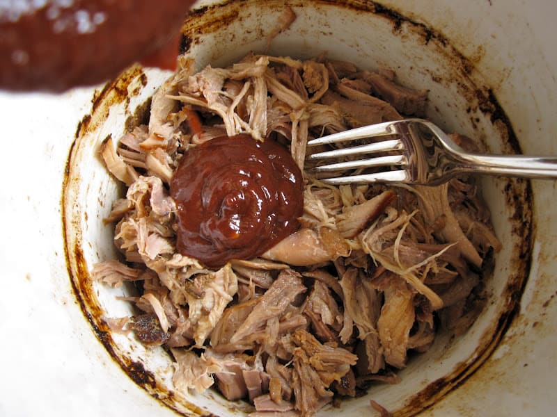 adding sauce to pulled pork