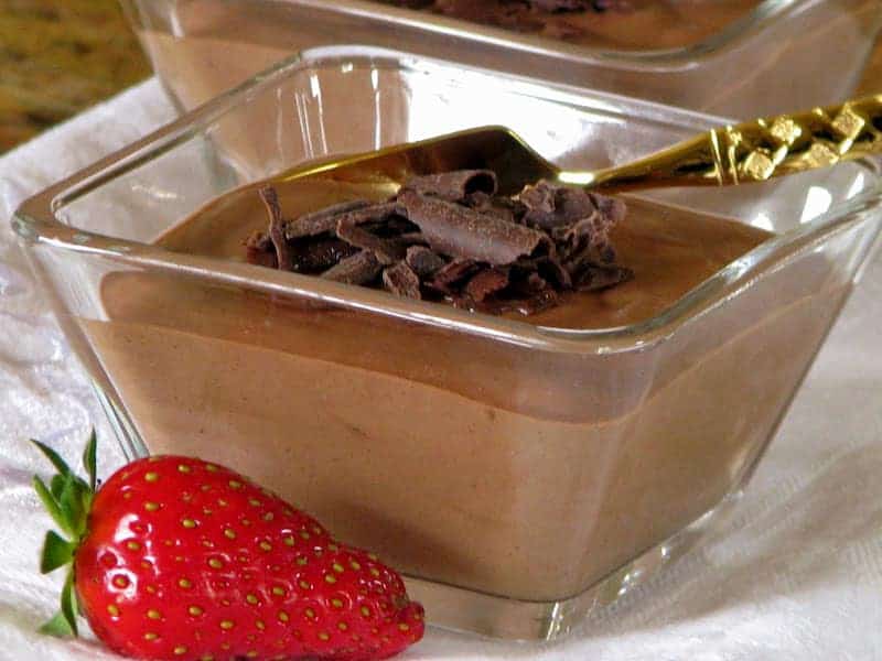chcocolate mousse in a glass bowl with gold spoon and strawberry