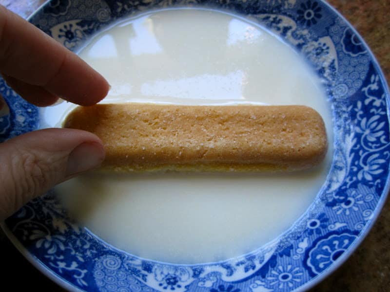 dipping the ladyfinger into the milk and limoncello mixture