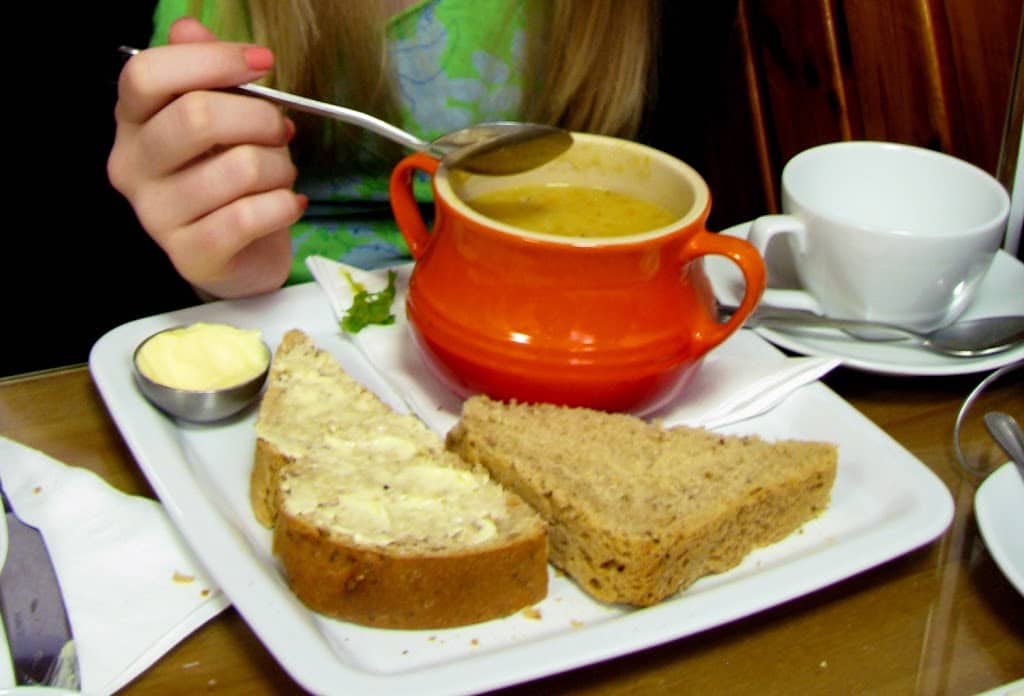 girl eating Scottish red lentil soup and brown bread and butter