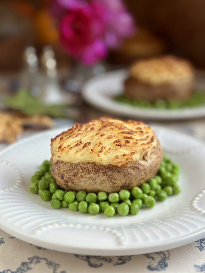 shepherd's pie baked potatoes on plate surrounded by peas