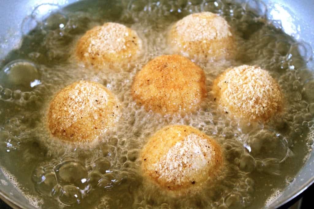 arancini frying in a pan