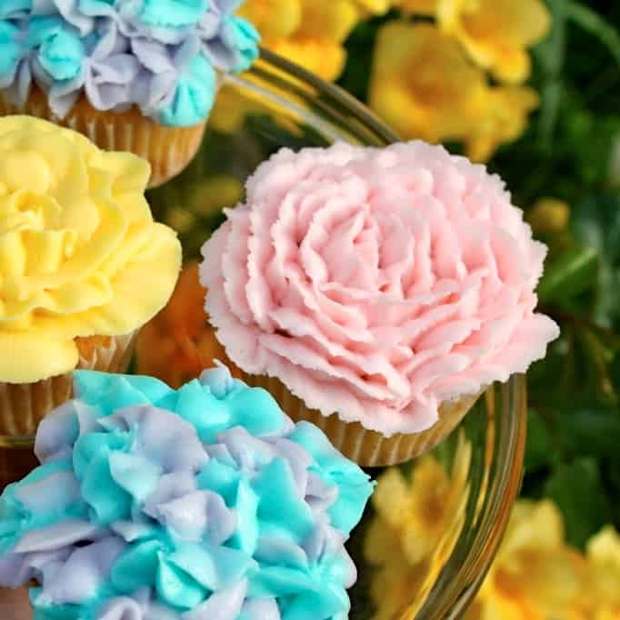 floral cupcakes decorated with buttercream on a cake plate outside