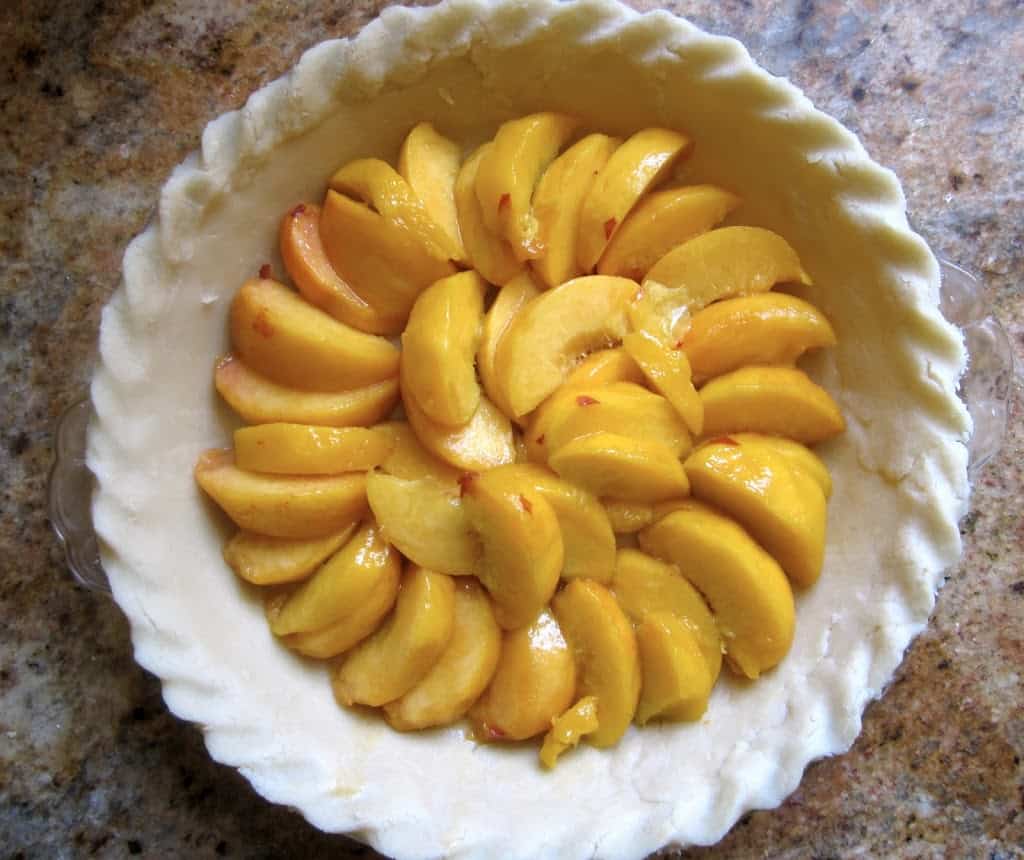 fresh peaches arranged in a pie crust
