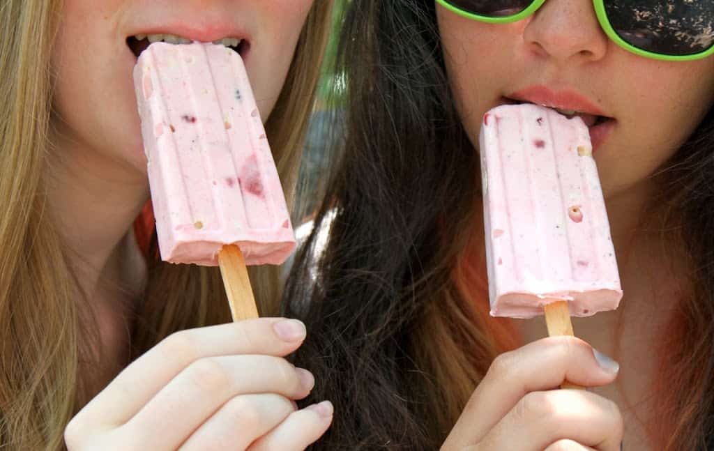 two girls eating strawberry meringue ice lollies