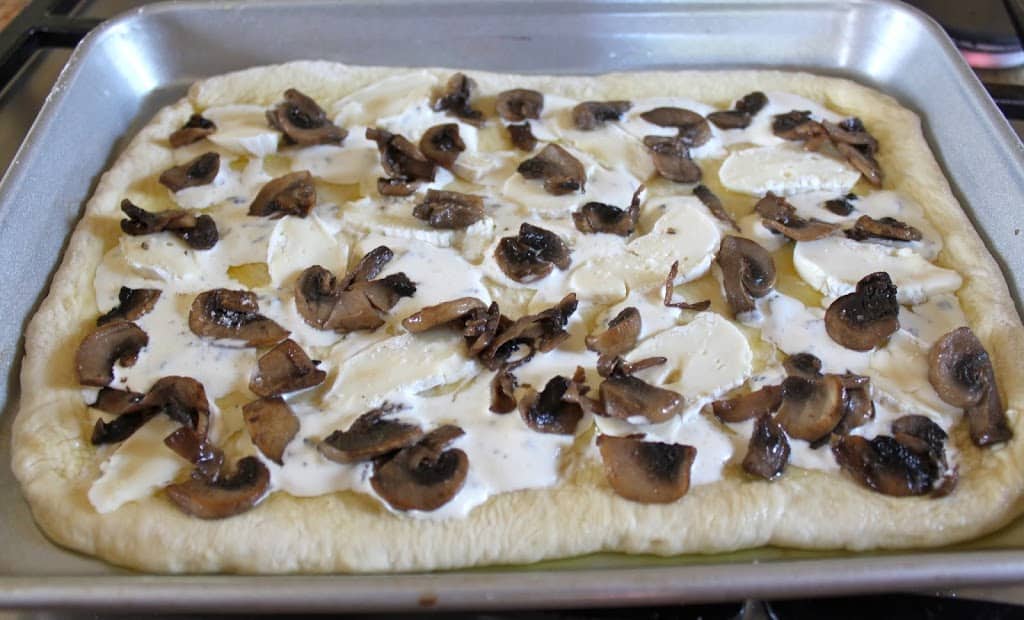 adding mushrooms to pizza dough