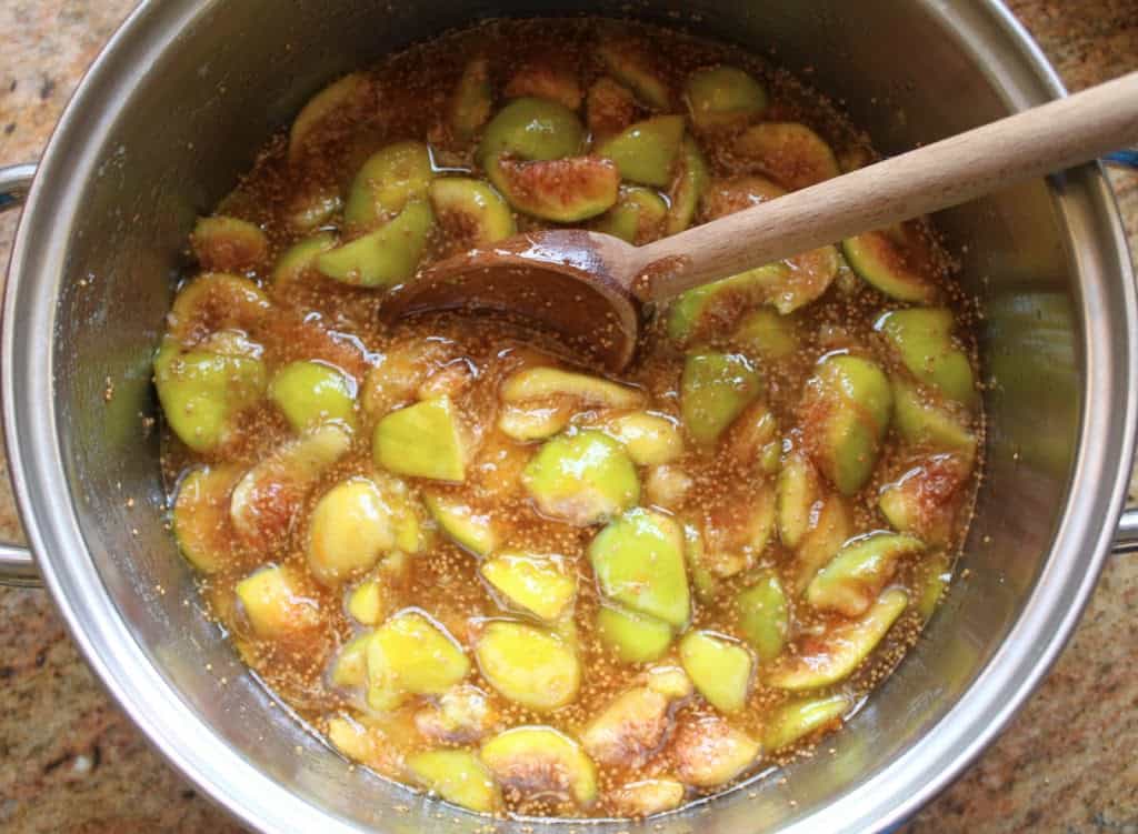 cooking the figs in a pot stirring with a wooden spoon