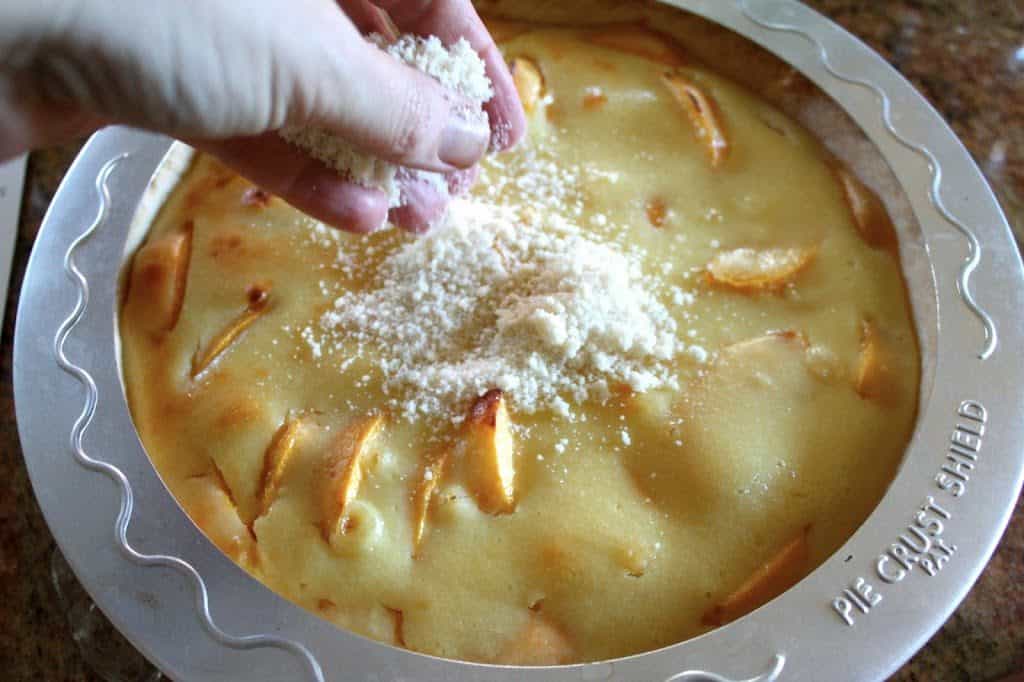 streusel being put on top of custard peach pie