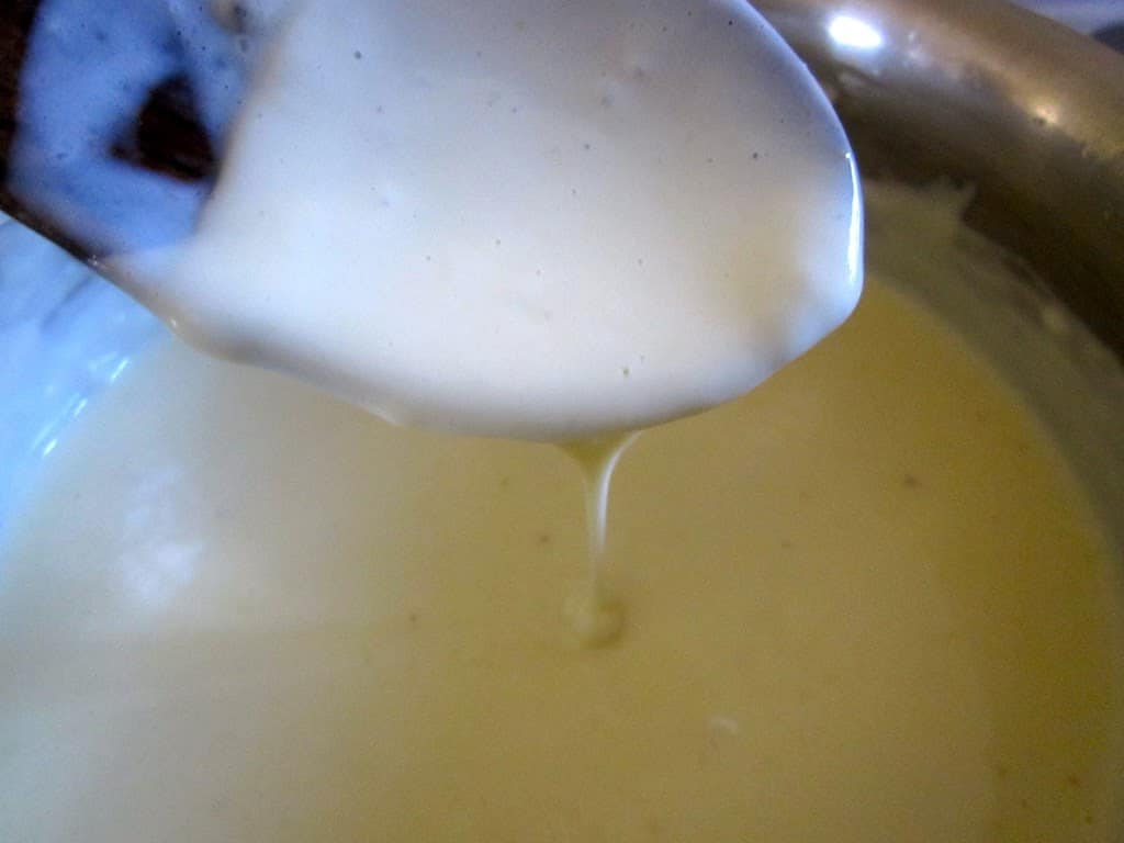white sauce dripping from a wooden spoon