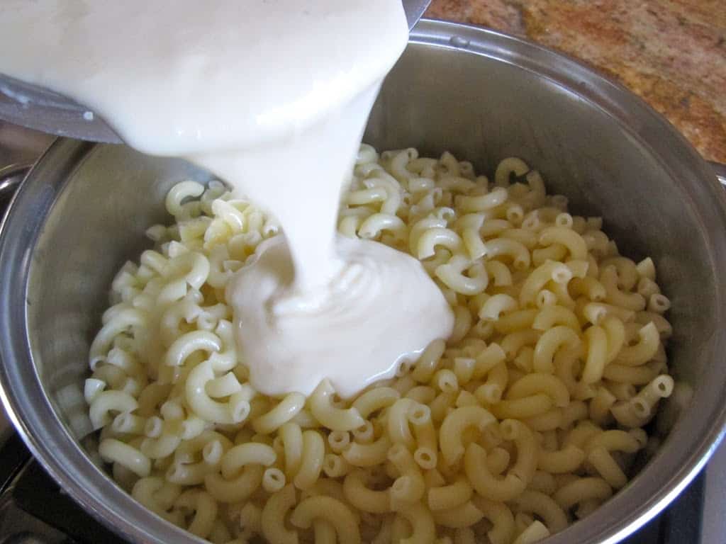 pouring cheese onto pasta 