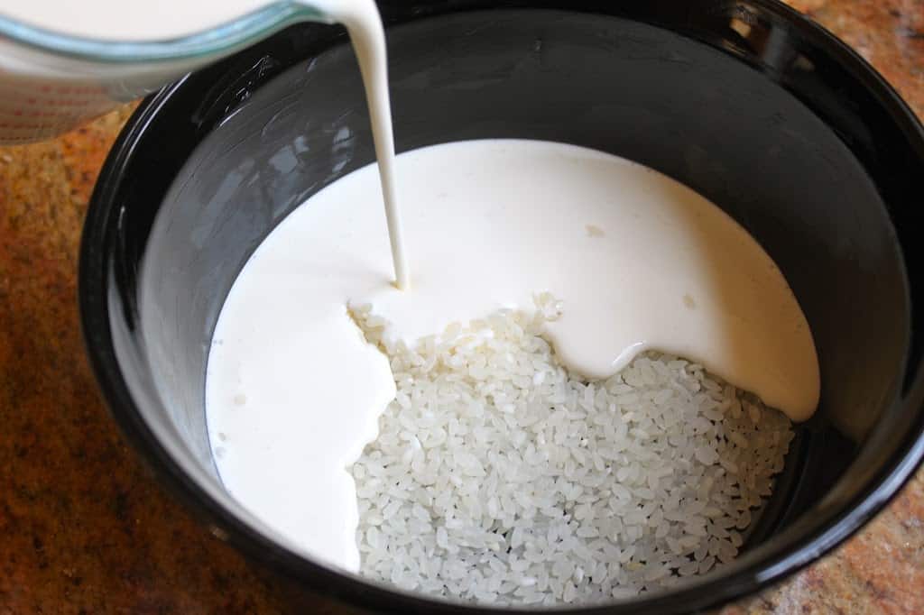 pouring cream into rice to make creamy rice pudding
