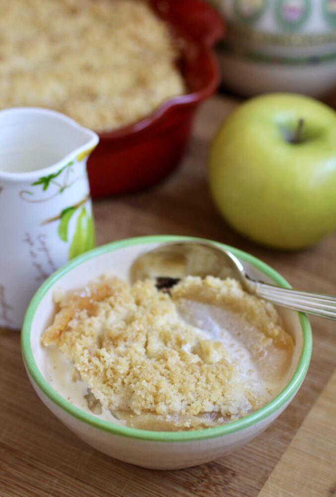 apple crumble and cream with apple and jug in background