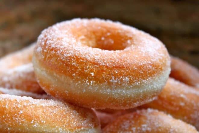 Classic sugar yeast donut on top of pile of other donuts