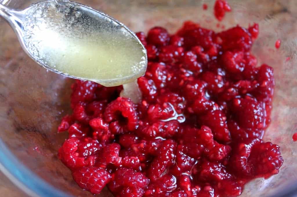 adding honey to raspberries
