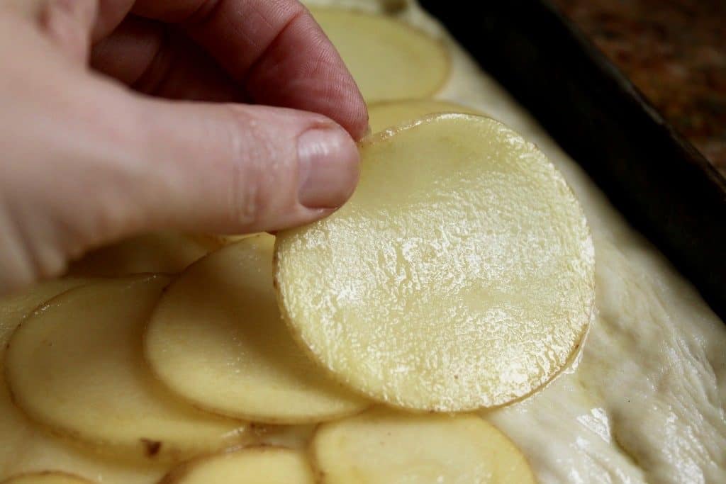 Layering potatoes onto potato pizza