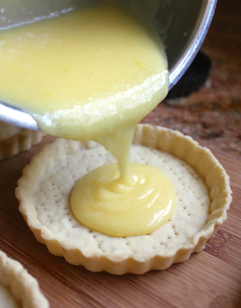 pouring passion fruit filling into tartlets