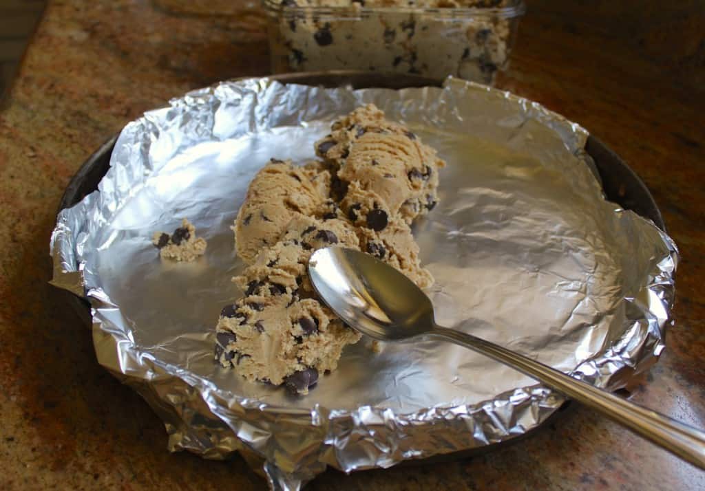 Putting chocolate chip cookie dough in pizza pan for a large birthday cookie