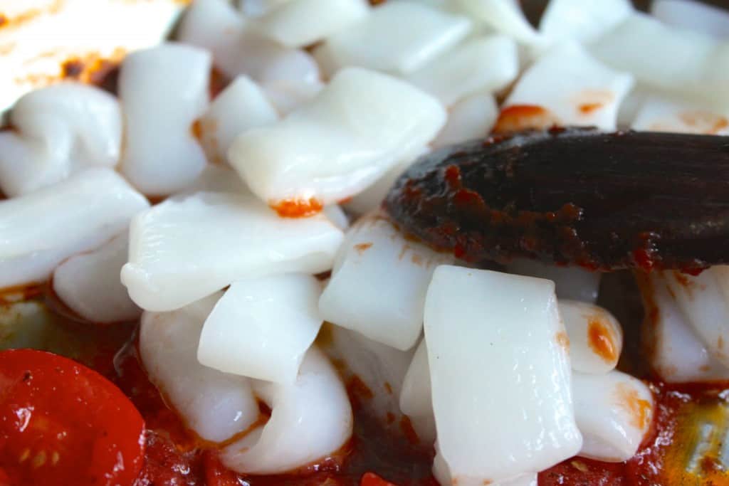 Adding calamari to the sauce for pasta with seafood sauce