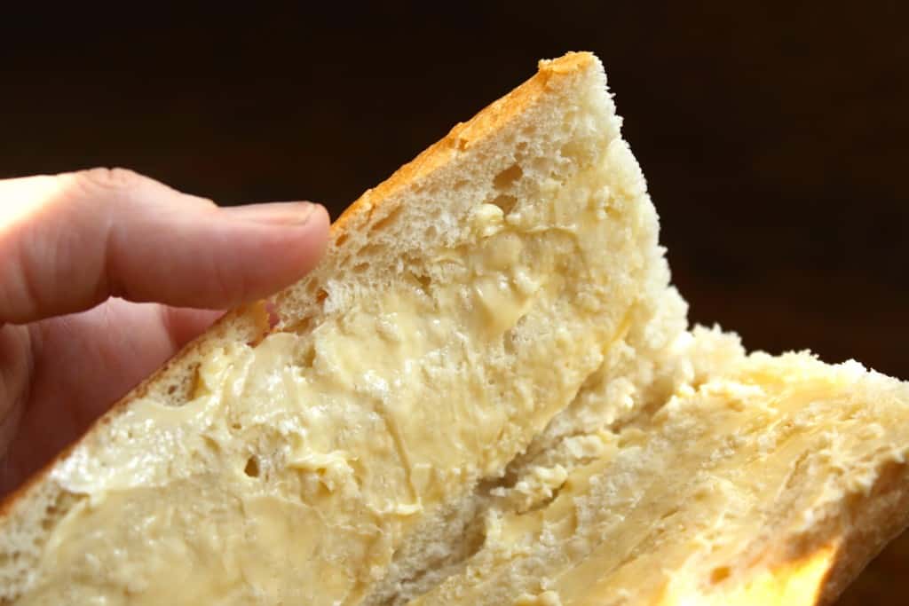 butter on a baguette for a jambon beurre