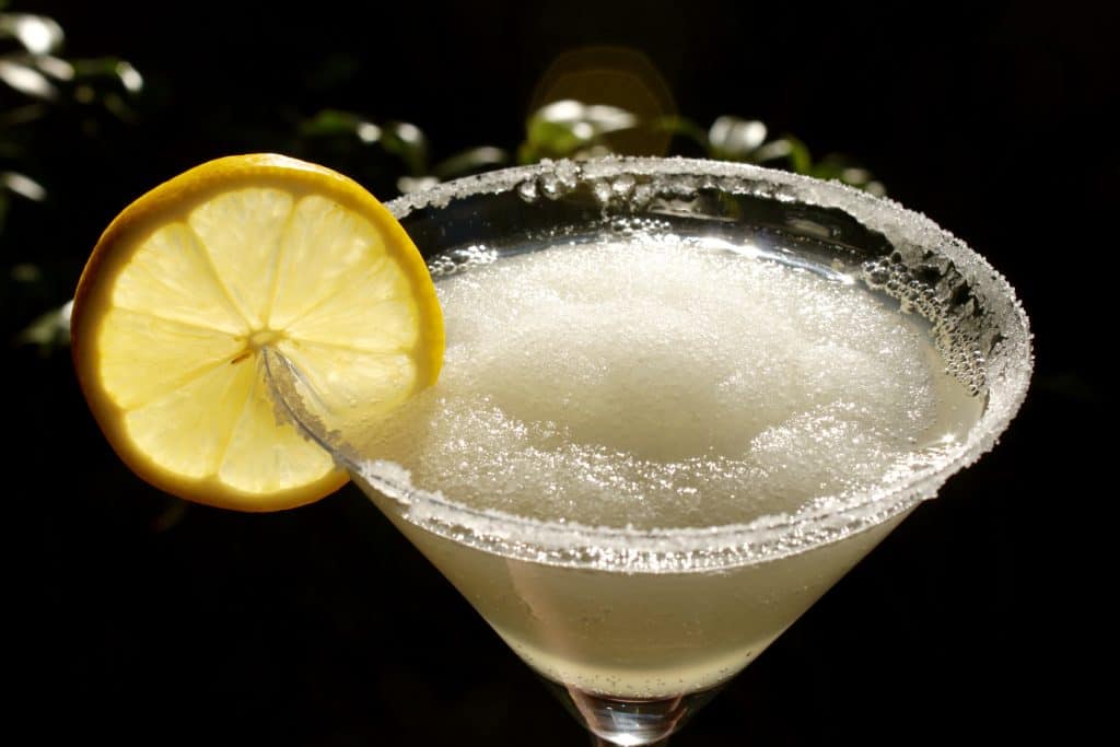 lemon drop slushie with a slice of lemon in a backlit photo 