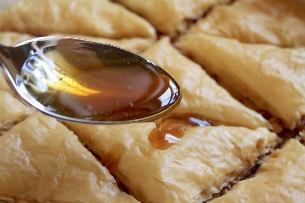 spooning hot honey over baked baklava recipe