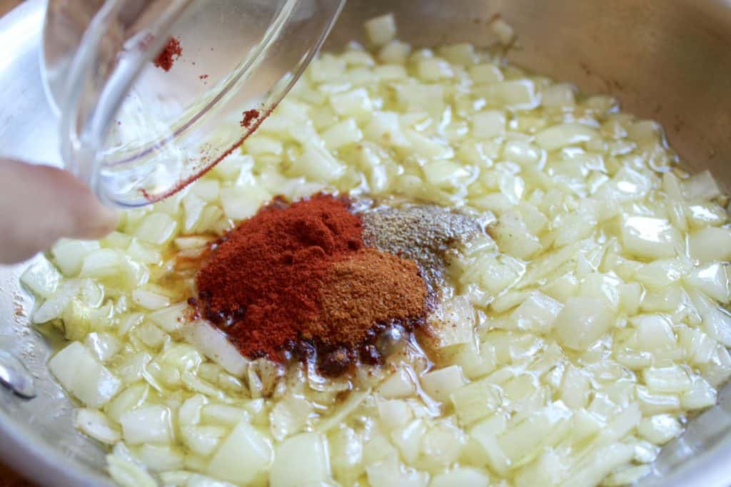 adding spices to onion in pan