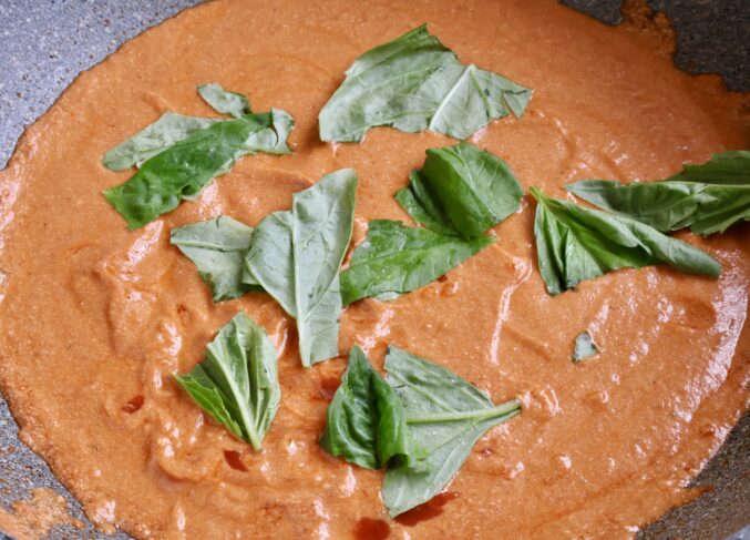 adding basil to sauce